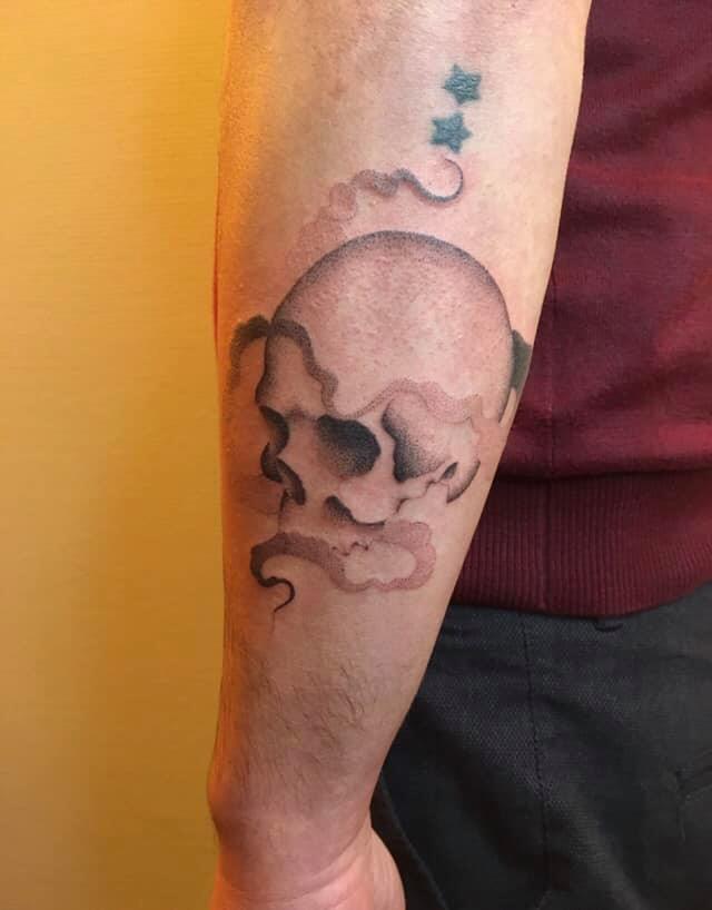 Un tatouage d'un crâne en travail de points entouré de fumée