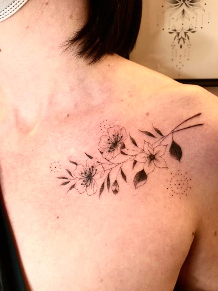 Un tatouage de fleurs en travail de points sur la clavicule