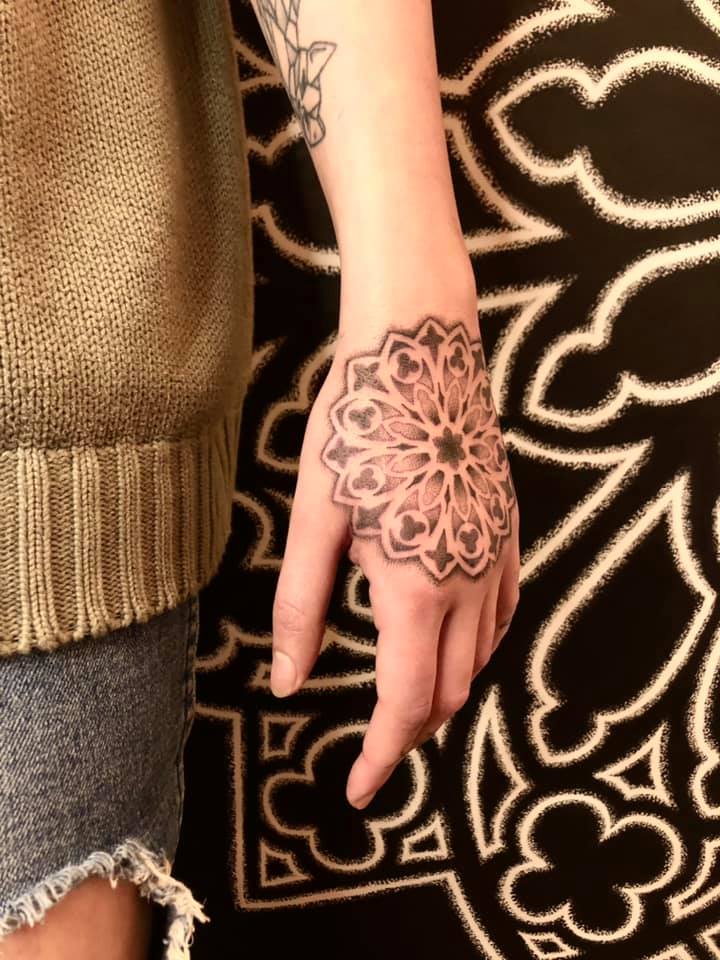 Un tatouage d'une rosace gothique en travail de points sur la main