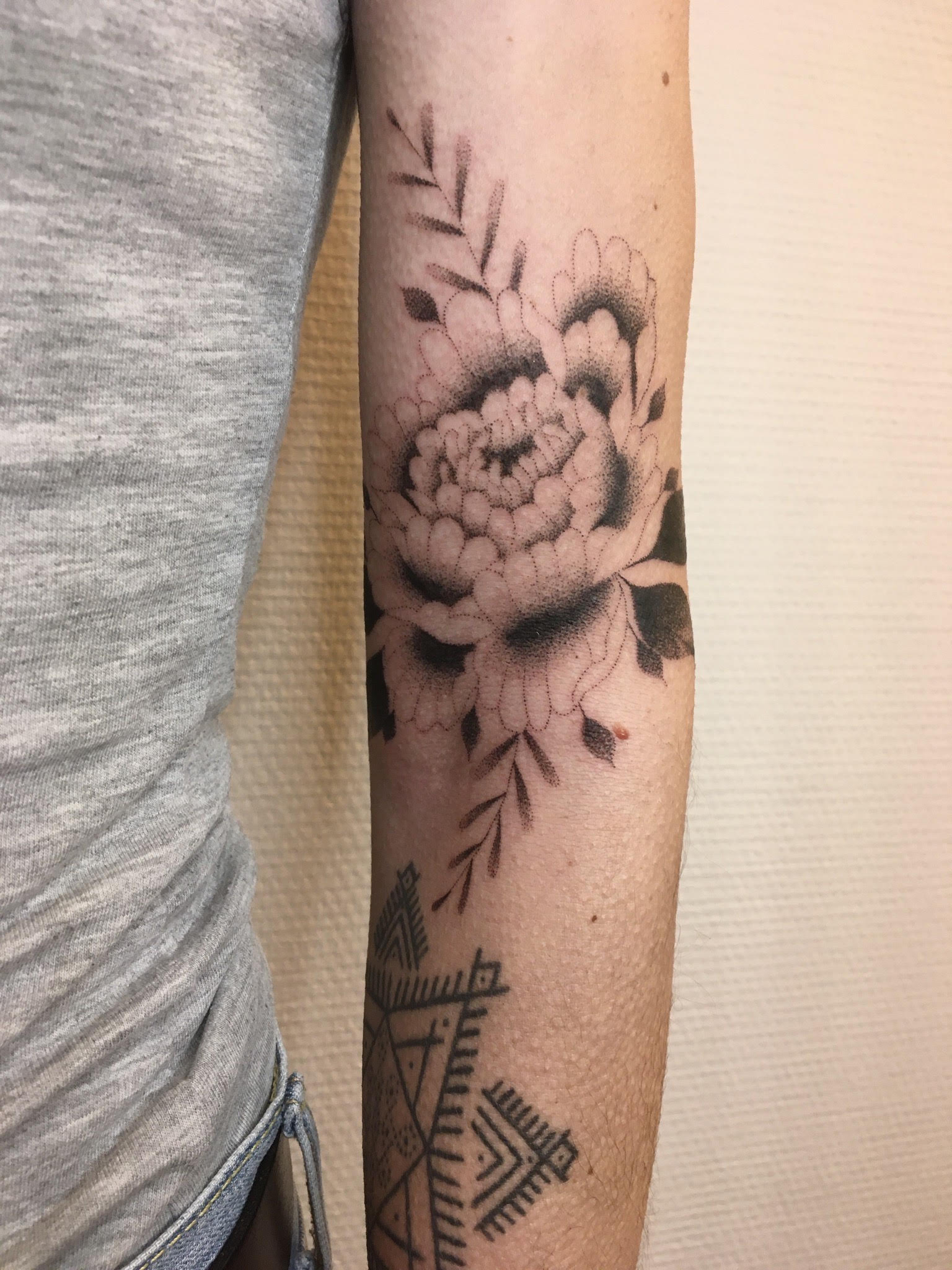 Un tatouage d'une grande rose en travail de points sur l'avant-bras